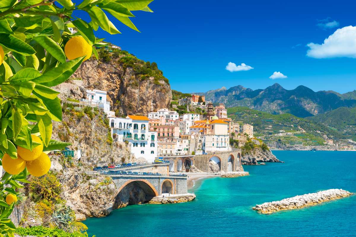Veduta di Amalfi in Campania con la città e il mare incorniciati da una pianta di limoni.