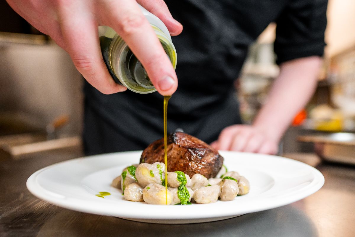 Olio extravergine versato a crudo su carne e gnocchi