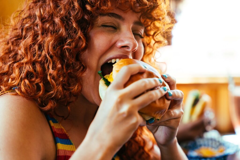 La ragazza addenta l'hamburger con un'espressione di puro piacere.