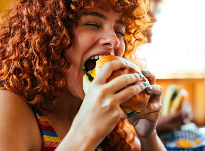 La ragazza addenta l'hamburger con un'espressione di puro piacere.