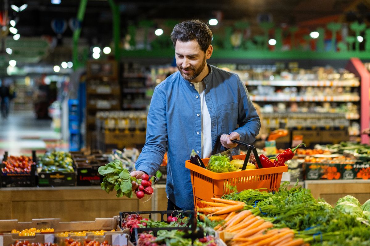 Uomo che fa la spesa al mercato della frutta e verdura.